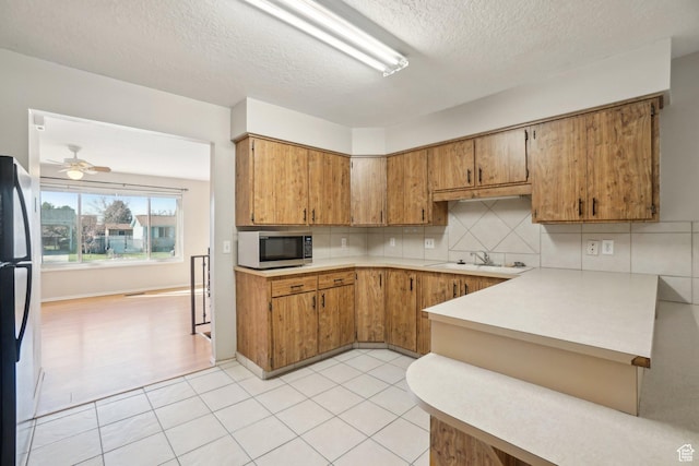 240 W 220 S, Orem, UT 84058 - kitchen featuring light countertops, tasteful backsplash, brown cabinetry, and stainless steel microwave