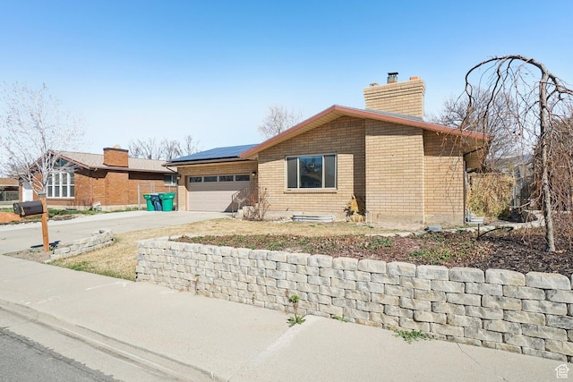240 W 220 S, Orem, UT 84058 - view of front of property with roof mounted solar panels, an attached garage, a chimney, brick siding, and driveway