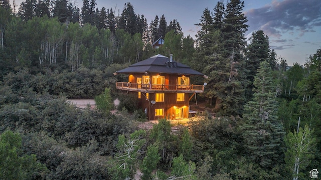 rear view of property featuring a deck and a view of trees