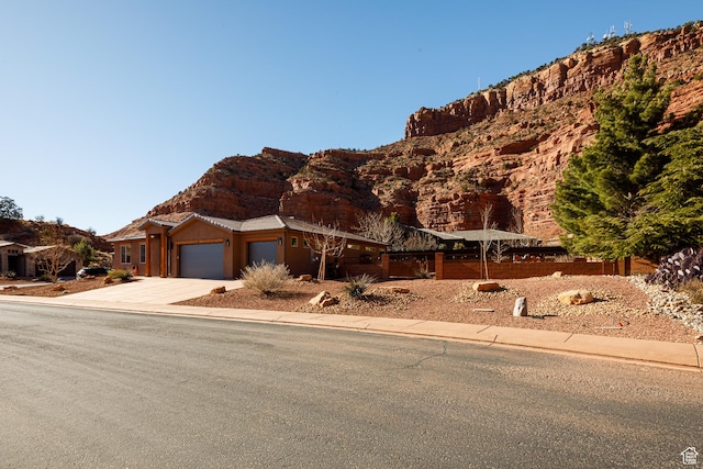 view of front of property with driveway, an attached garage, and fence