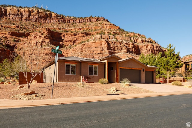 533 E Cutter Trl, Kanab, UT 84741 - view of front facade with driveway, a garage, stucco siding, and a mountain view