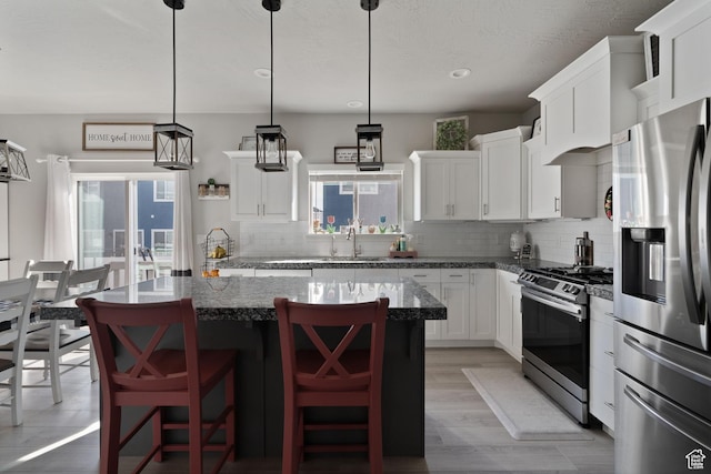 7016 N Amber Mead Ave, Eagle Mountain, UT 84005 - kitchen with a center island, tasteful backsplash, appliances with stainless steel finishes, white cabinetry, and a kitchen breakfast bar