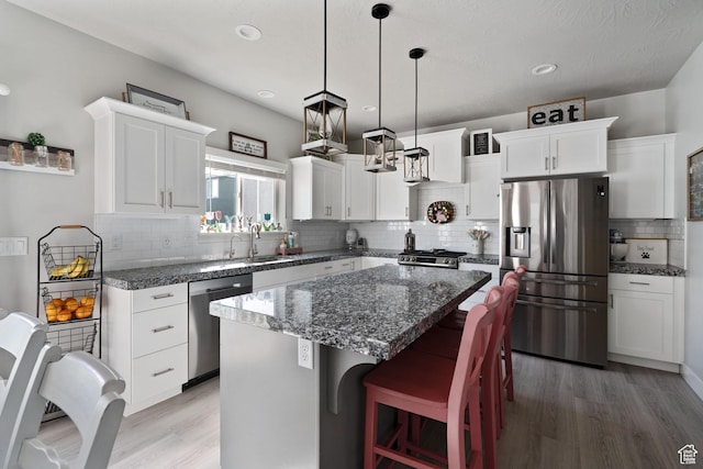 7016 N Amber Mead Ave, Eagle Mountain, UT 84005 - kitchen featuring a sink, a kitchen island, white cabinetry, light wood-style flooring, and stainless steel appliances