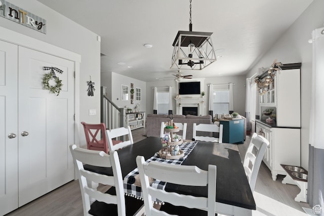 7016 N Amber Mead Ave, Eagle Mountain, UT 84005 - dining room with a fireplace, wood finished floors, stairway, and ceiling fan with notable chandelier