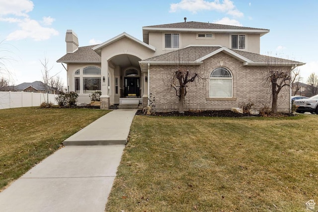view of front of property featuring stucco siding, roof with shingles, fence, a front yard, and a chimney