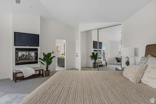 carpeted bedroom with baseboards, connected bathroom, a closet, and vaulted ceiling