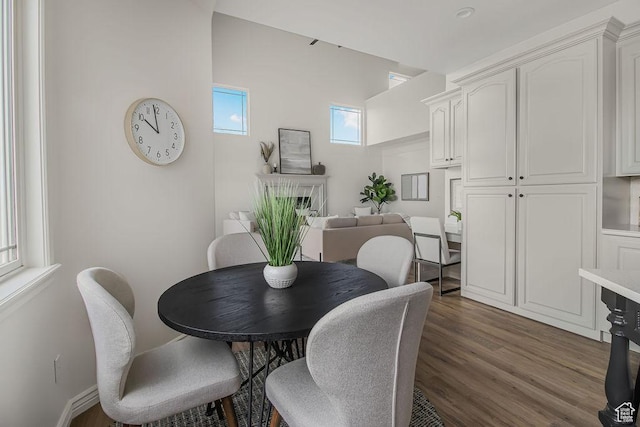 dining room with a fireplace, dark wood finished floors, and baseboards