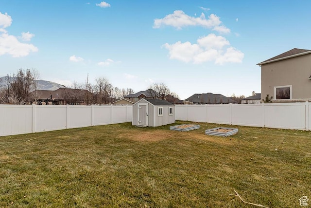 view of yard featuring a fenced backyard, a vegetable garden, and a storage shed