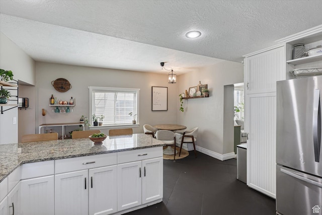 kitchen featuring open shelves, light stone countertops, white cabinets, and freestanding refrigerator