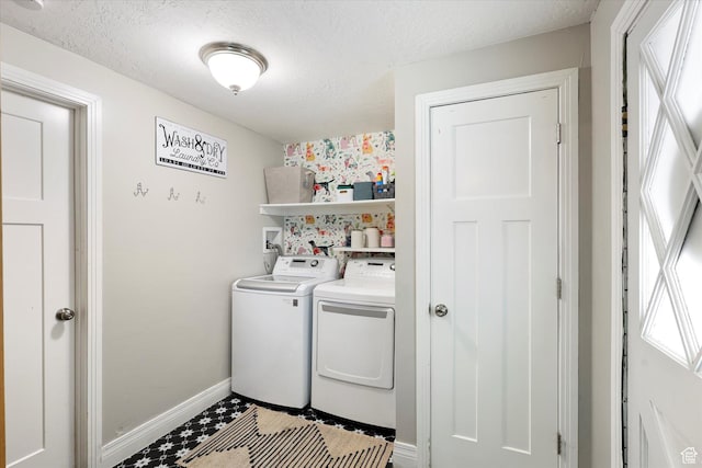 laundry room with washing machine and clothes dryer, a textured ceiling, baseboards, and laundry area