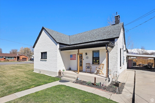 view of front of property featuring covered porch, a chimney, brick siding, and a front yard
