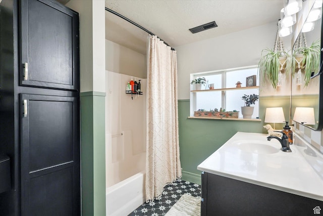 bathroom featuring a textured ceiling, visible vents, shower / tub combo, and vanity