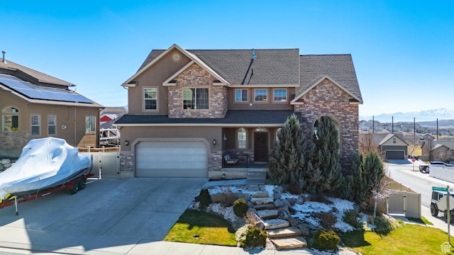 view of front of house featuring driveway, stone siding, stucco siding, fence, and a garage