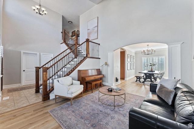 living room with arched walkways, stairway, a notable chandelier, and light wood finished floors