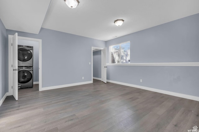 interior space with baseboards, wood finished floors, and stacked washer and clothes dryer