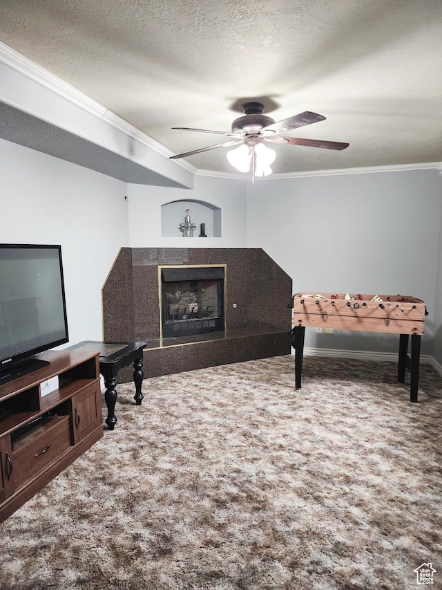 living room with a textured ceiling, carpet flooring, ornamental molding, and a ceiling fan