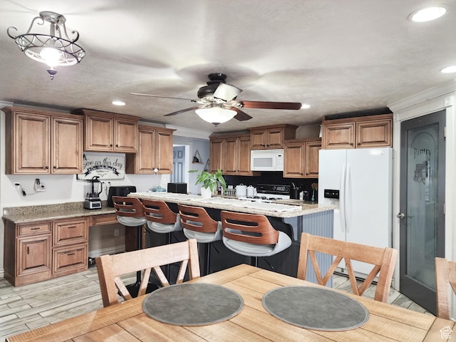 kitchen featuring white appliances, ornamental molding, light wood finished floors, a ceiling fan, and brown cabinetry