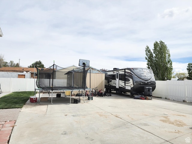 view of vehicle parking featuring fence and a trampoline