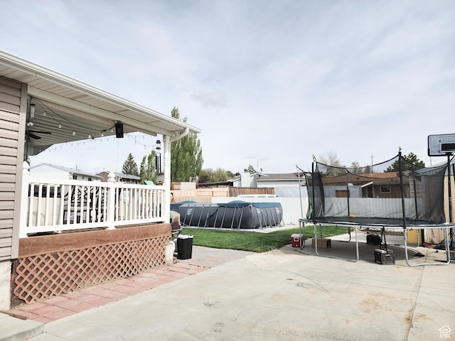 view of patio with fence, a trampoline, and a wooden deck