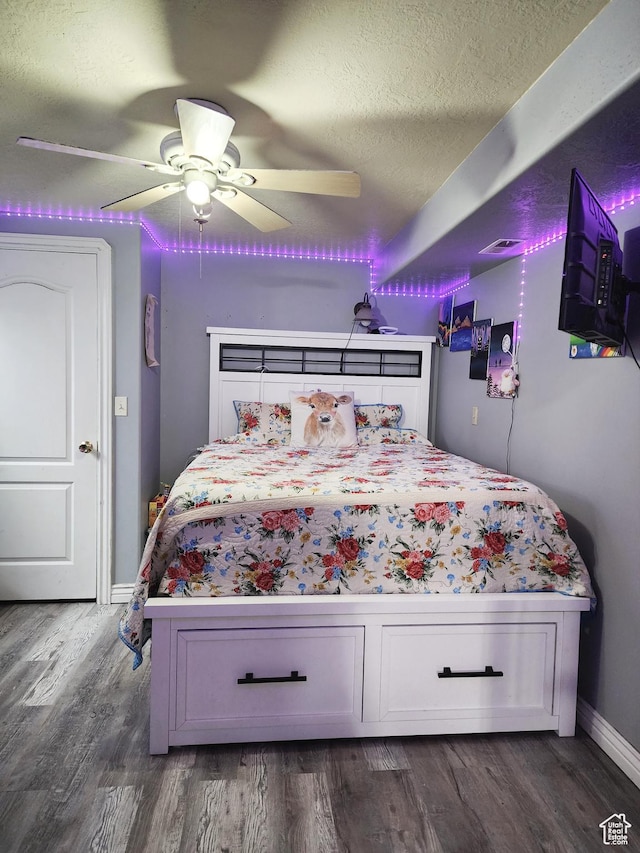 bedroom with baseboards, dark wood-style flooring, a textured ceiling, and a ceiling fan