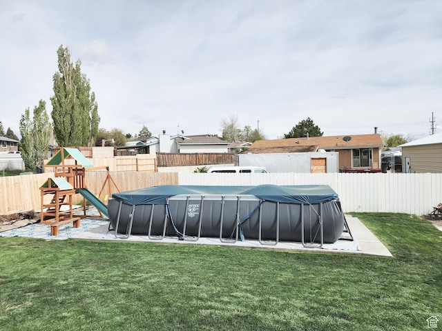 view of yard with a fenced backyard, a playground, and a fenced in pool