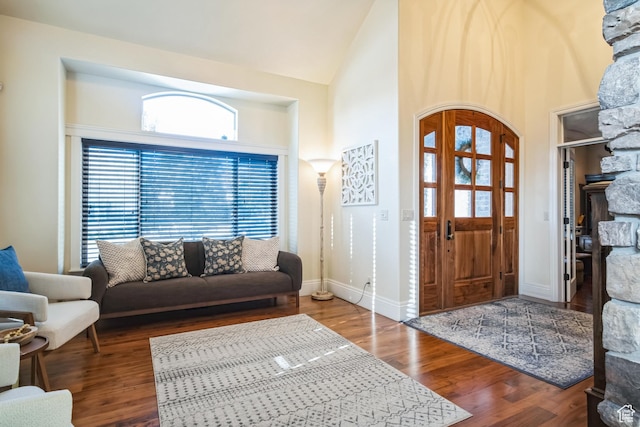 foyer with a fireplace, baseboards, high vaulted ceiling, and wood finished floors