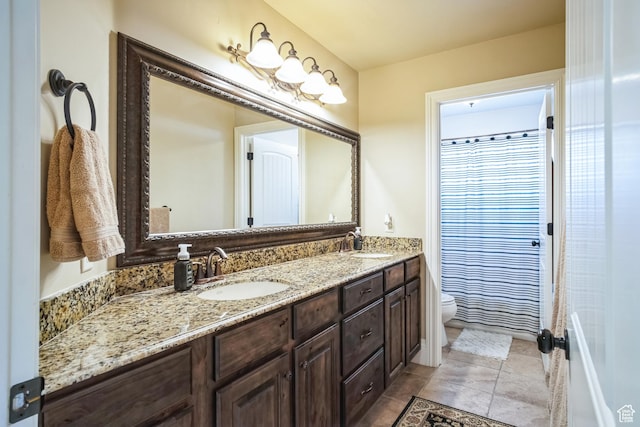 full bath featuring double vanity, a sink, toilet, and tile patterned flooring