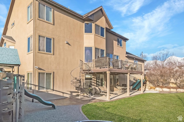 rear view of property with stucco siding, stairs, playground community, and a patio area