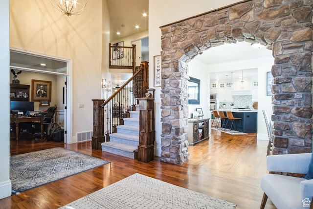 entryway with stairway, ornamental molding, arched walkways, visible vents, and wood finished floors