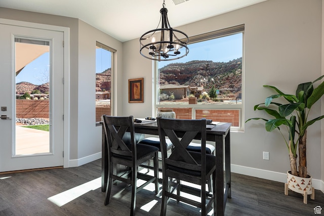 dining space with dark wood finished floors, a notable chandelier, and plenty of natural light