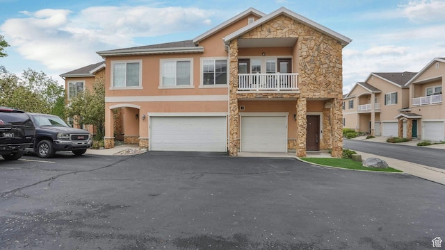 1138 S Meadow Fork Rd E Unit 3, Provo, UT 84606 - view of front of house featuring stone siding, a garage, stucco siding, asphalt driveway, and a balcony