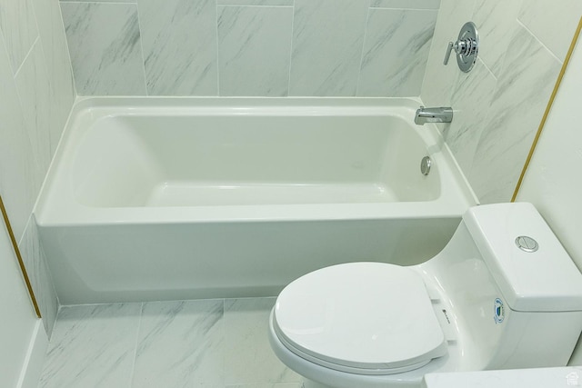 bathroom featuring a tub, marble finish floor, and toilet