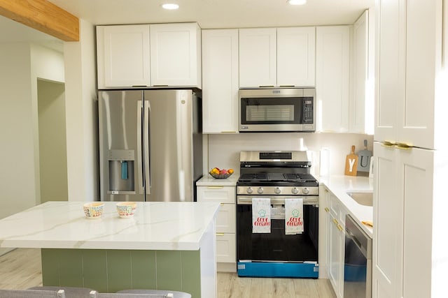 kitchen with a kitchen island, white cabinetry, light stone countertops, appliances with stainless steel finishes, and recessed lighting