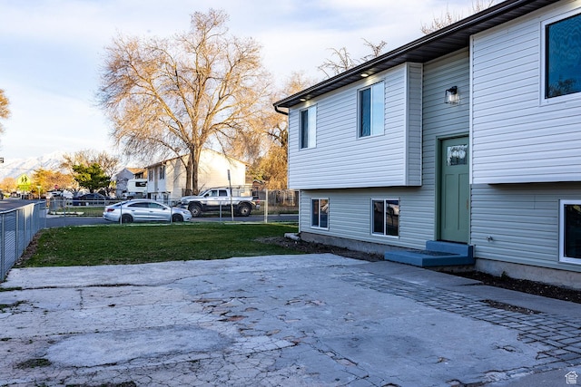 view of side of home featuring a lawn and fence
