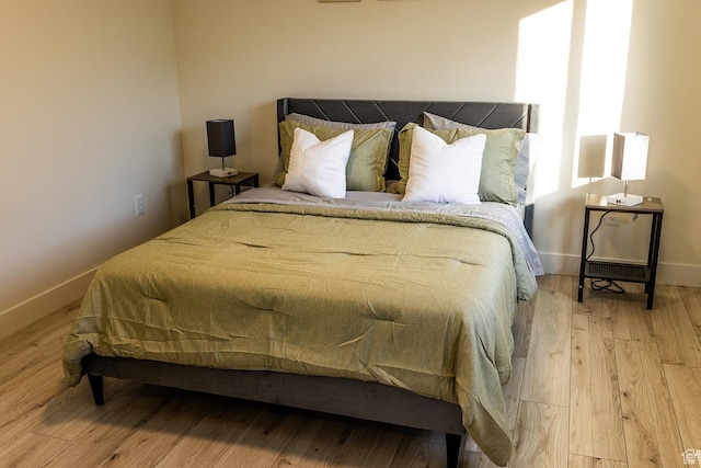 bedroom featuring light wood finished floors and baseboards