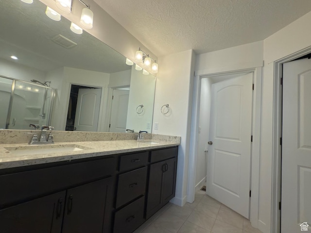 5264 S Tucker Ct W Unit 329, West Valley City, UT 84118 - bathroom with a textured ceiling, a shower stall, tile patterned floors, a sink, and double vanity