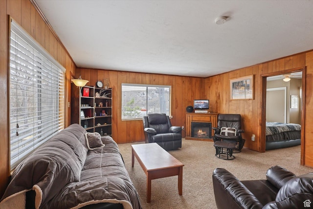 living area with carpet floors, wooden walls, and a lit fireplace