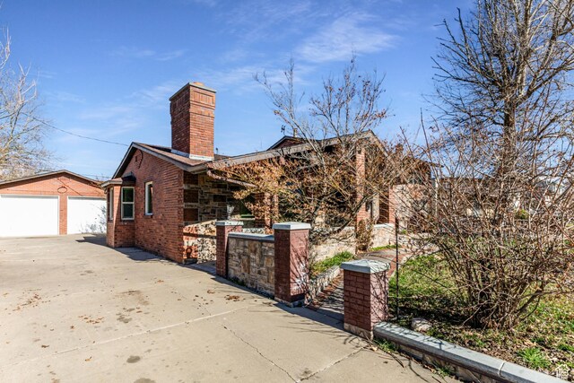 945 Church St, Layton, UT 84041 - view of home's exterior with fence, a chimney, a garage, brick siding, and an outbuilding