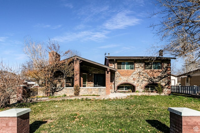rear view of property featuring stone siding, a lawn, a fireplace, and a chimney