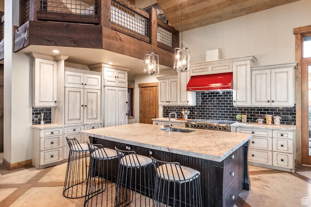 5956 N Triple Crown Trl, Oakley, UT 84055 - kitchen with a breakfast bar, premium range hood, an island with sink, a sink, and backsplash