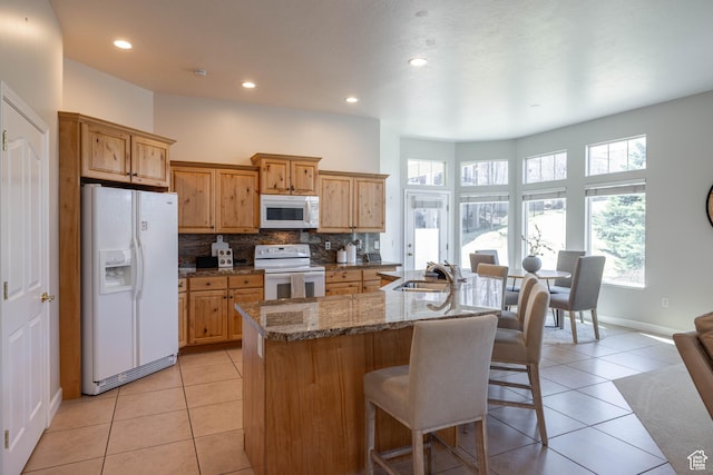 14146 S Spyglass Hill Dr, Draper, UT 84020 - kitchen featuring white appliances, a kitchen breakfast bar, light tile patterned flooring, a sink, and tasteful backsplash