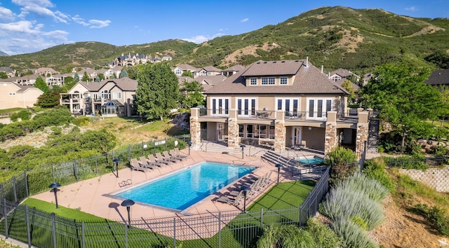 14146 S Spyglass Hill Dr, Draper, UT 84020 - back of house with stone siding, a patio area, a fenced backyard, and a balcony