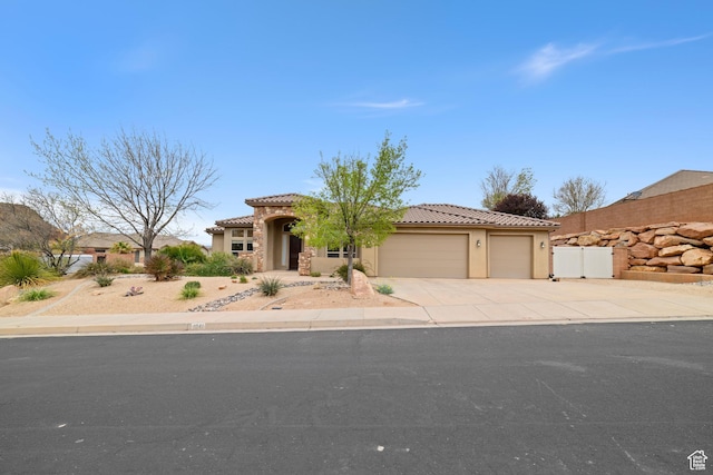 view of front of home with fence, a tiled roof, an attached garage, concrete driveway, and stucco siding