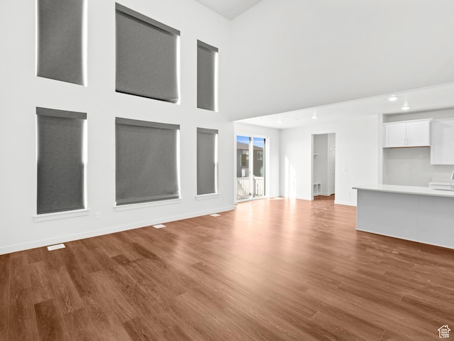 963 W Ruddy Clover Ln Unit 282, Saratoga Springs, UT 84045 - unfurnished living room featuring baseboards, a towering ceiling, and wood finished floors