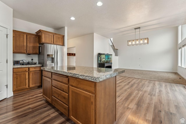 4 E Sterling Loop, Vineyard, UT 84059 - kitchen featuring a kitchen island, stainless steel fridge with ice dispenser, a textured ceiling, brown cabinetry, and dark wood-type flooring