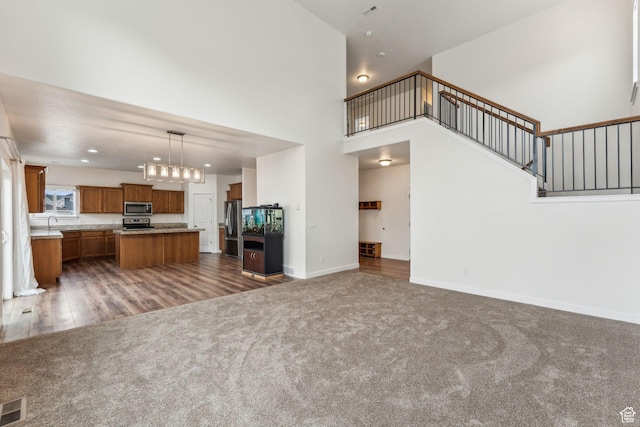 4 E Sterling Loop, Vineyard, UT 84059 - unfurnished living room with a notable chandelier, dark carpet, stairway, baseboards, and a towering ceiling