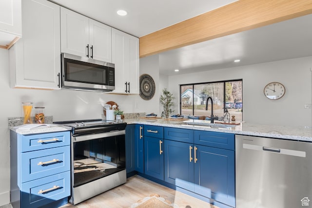 223 N Harrison Blvd, Ogden, UT 84404 - kitchen with white cabinetry, blue cabinets, a sink, light stone counters, and appliances with stainless steel finishes