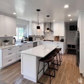 5188 S Saddleback Dr, Holladay, UT 84117 - kitchen with white cabinets, a kitchen breakfast bar, a kitchen island, and wall chimney range hood