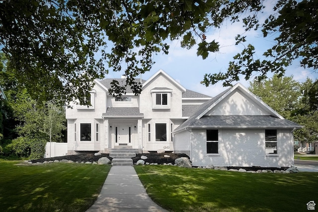 view of front facade featuring a shingled roof and a front yard