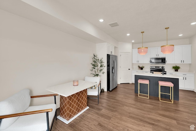 499 N 420 W Unit 138, Lindon, UT 84042 - kitchen featuring light countertops, white cabinets, dark wood finished floors, appliances with stainless steel finishes, and a breakfast bar area